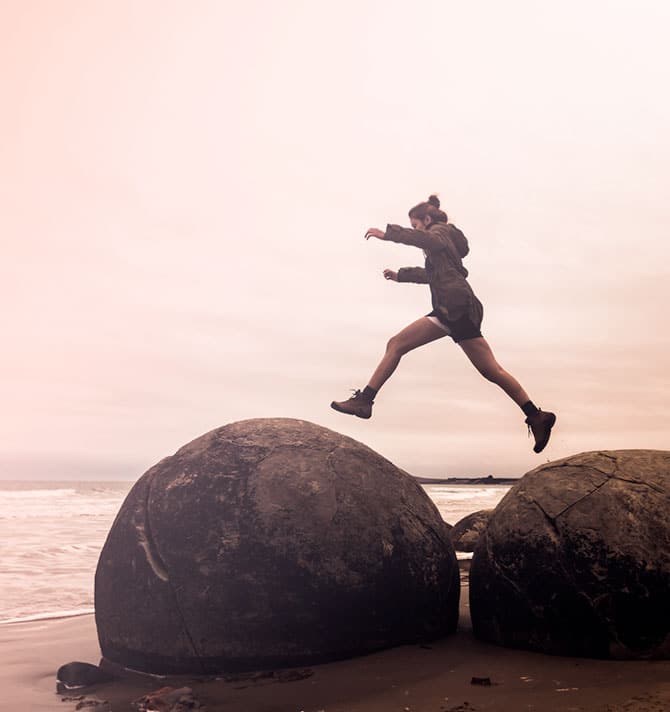 hiker jumping over boulder